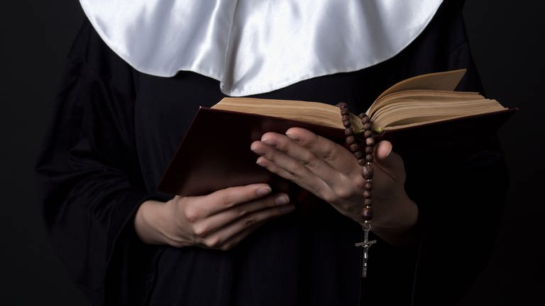 Nonne die Bibel in den Händen hält (Foto: Colourbox)