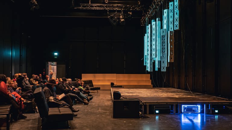 Die Bühne mit der Projektionsfläche mit Stuhlreihen auf denen das Publikum sitzt (Foto: SWR, Oliver Reuther)