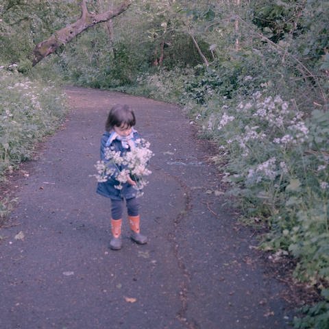 kleines Kind mit Blumen auf einem Waldweg (Foto: IMAGO, IMAGO / Hans Lucas)
