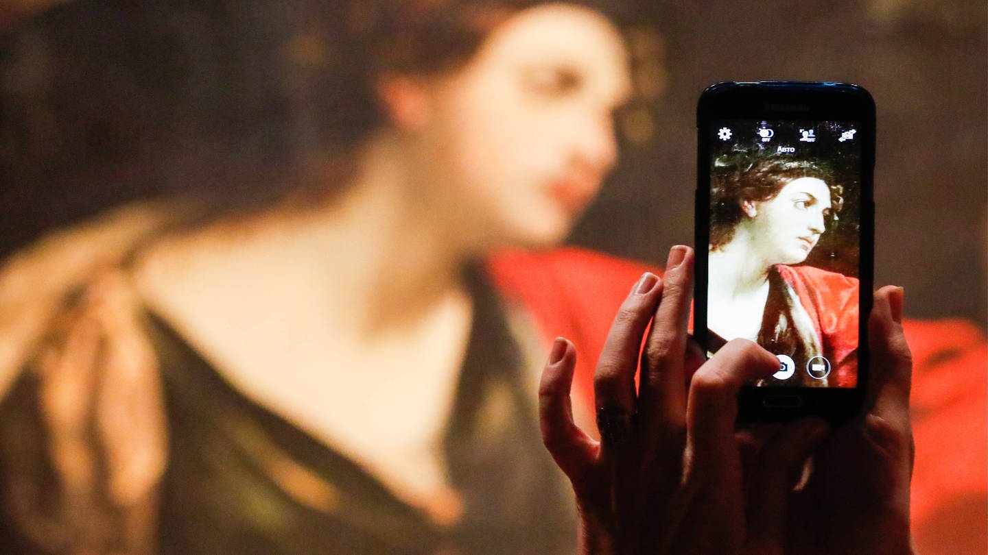 Eine Frau fotografiert ein Gemälde von Guido Reni
