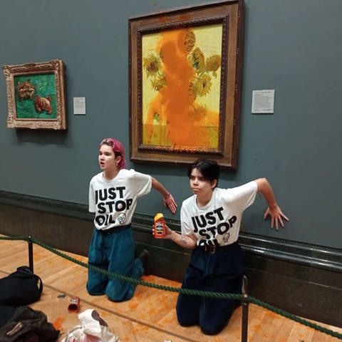 Zwei Aktivistinnen haben ihre Hände in London an eine Museumswand geklebt, nachdem sie Suppe auf Vincent Van Goghs „Sonnenblumen“ geschmiert hatten (Foto: IMAGO, IMAGO / ZUMA Wire / Just Stop Oil)
