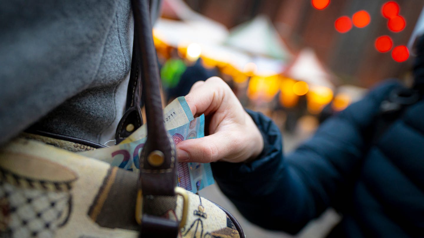 Taschendiebstahl: Eine Hand zieht Geldscheine aus einer Handtasche (Foto: IMAGO, Agentur 54 Grad)