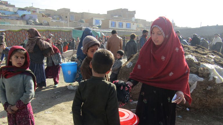 Eine Frau verteilt Decken, Matten und andere überlebenswichtige Güter. (Foto: Afghanischer Frauenverein e.V.)