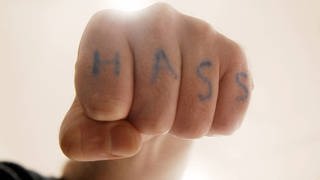 Die Aufschrift „Hass ” auf einer Faust (Foto: imago images, imago stock&people / IMAGO / Seeliger)