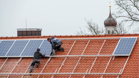 Arbeiter installieren Solarzellen auf einem Dach in Ingolstadt (Foto: picture-alliance / Reportdienste, picture alliance / Daniel Kalker | Daniel Kalker)