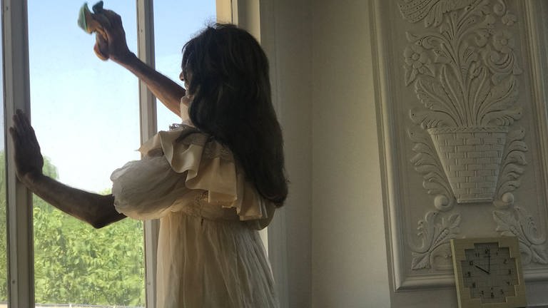 Hamideh im weißen Kleid beim Fensterputzen  (Foto: Dominika Nooripoor )