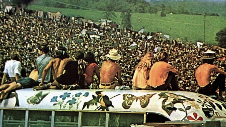 In Woodstock sitzen Festivalbesucher auf einem Bus und blicken auf die Menschenmasse (Foto: IMAGO, United Archives)