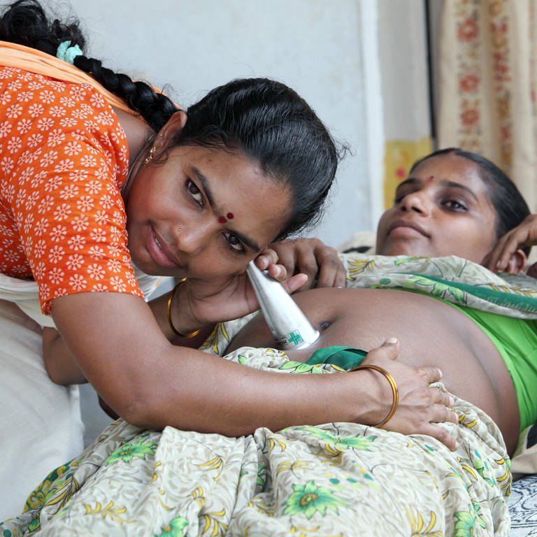 Indien - Mit einem Hebammenstethoskop horcht eine Hebamme den Bauch einer jungen Frau ab (Foto: IMAGO, Stefan Trappe)