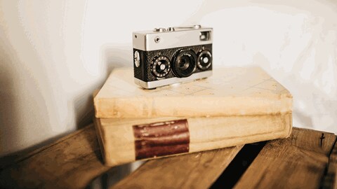 Vintage Fotokamera und Stapel alter Bücher auf Holzkiste im gemütlichen Schlafzimmer (Foto: IMAGO, xGustavoxPozox)