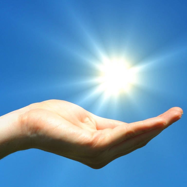 Eine geöffnete Hand unter einer strahlenden Sonne (Foto: IMAGO, imago images/YAY Images/gunnar3000 1108264)