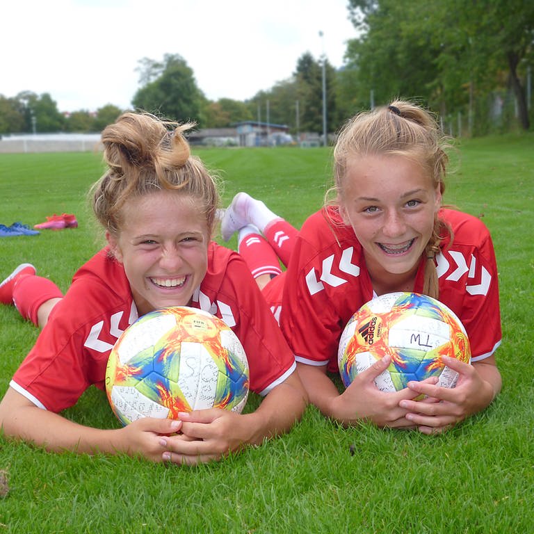 zwei junge Fußballspielerinnen liegen im Gras und lachen in die Kamera (Foto: Martina Keller)