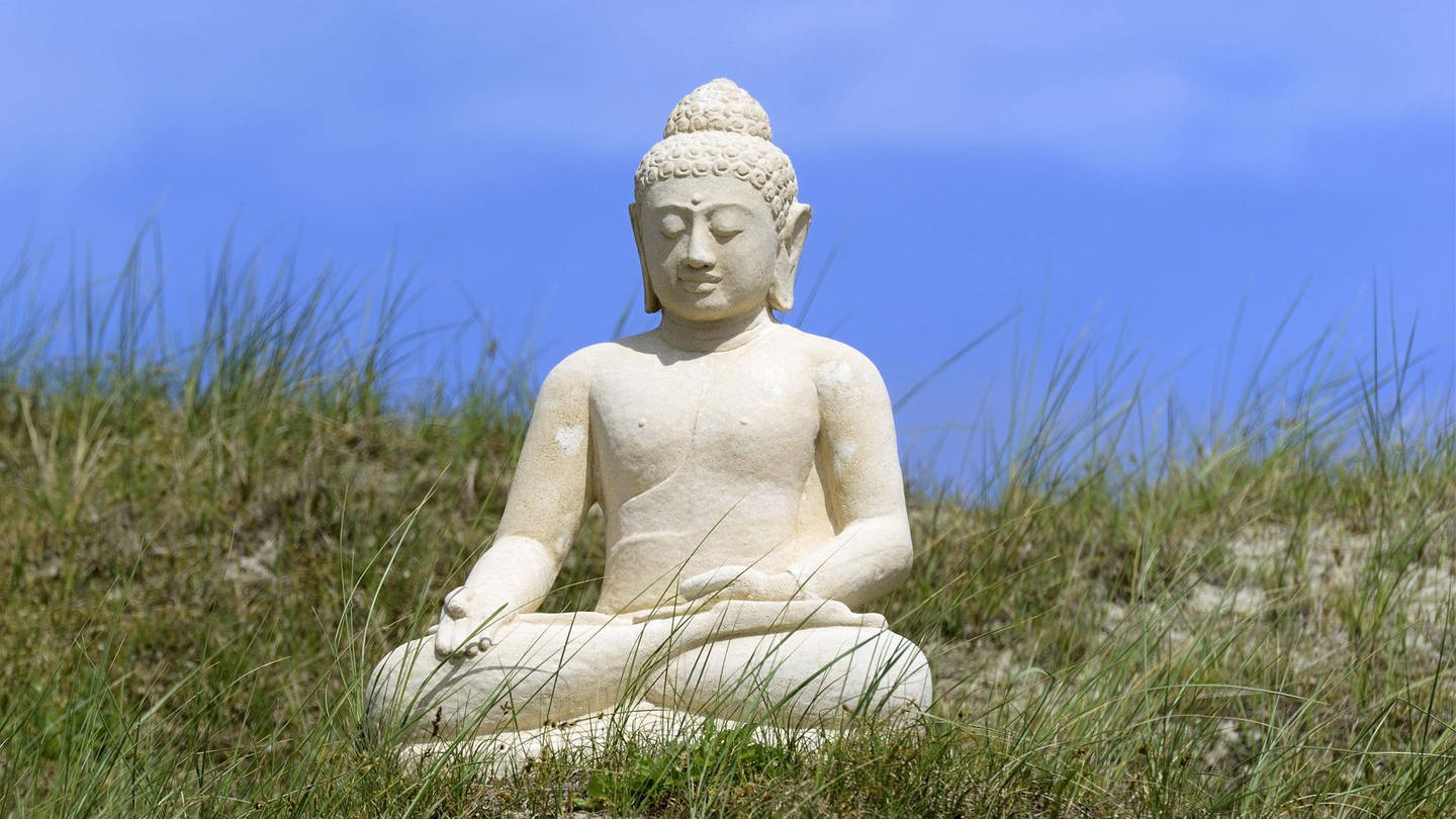 Eine Buddha-Skulptur in der Dünenlandschaft von Norderney (Foto: IMAGO, imageBROKER/Frederik ibxrba04531455.jpg)