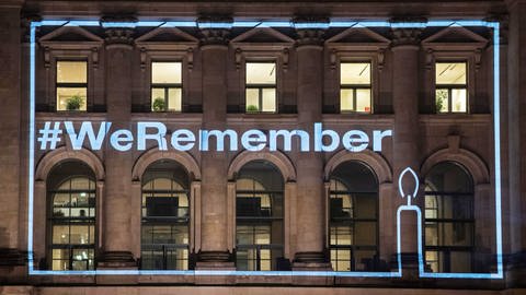 Fassade des Reichstagsgebäudes bei Nacht, angestrahlt mit dem Schriftzug #WeRemember, anlässlich des Holocaust-Gedenktages 2022 (Foto: picture-alliance / Reportdienste, picture alliance/dpa | Paul Zinken)