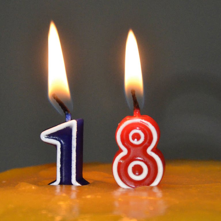 18 Jahre - endlich volljährig. Kerzen mit der Zahl 18 auf einer Geburtstagstorte (Foto: IMAGO, Christine Roth)