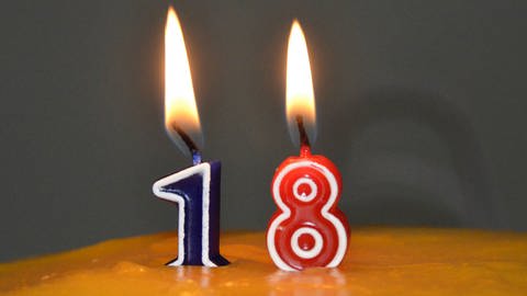 18 Jahre - endlich volljährig. Kerzen mit der Zahl 18 auf einer Geburtstagstorte (Foto: IMAGO, Christine Roth)