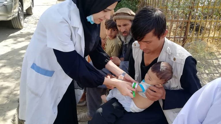Ein Arzt kümmert sich um ein Kind. Mobile medizinische Versorgung für Binnenvertriebene. (Foto: Afghanischer Frauenverein e.V.)
