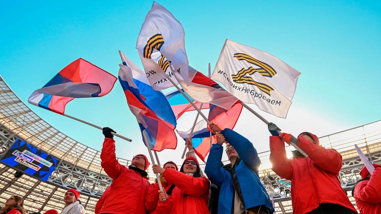 Menschen mit der russischen Nationalflaggen und den Flaggen mit dem Buchstaben "Z" (Foto: picture-alliance / Reportdienste, picture alliance / ASSOCIATED PRESS | Ramil Sitdikov)