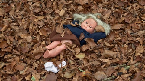 Symbolfoto sexueller Missbrauch, Puppe mit hochgezogenem Rock und entblößtem Unterleib liegt im Laub (Foto: picture-alliance / Reportdienste,  imageBROKER | Olaf Heil)