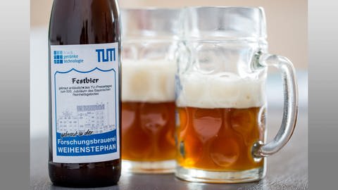 Eine Bierflasche mit dem Etiket der TU München ist in München (Bayern) neben zwei gefüllten Bierkrügen zu sehen. (Foto: picture-alliance / Reportdienste, Marc Müller)