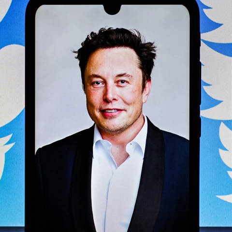 Elon Musk auf einem Handybildschirm, im Hintergrund das Twitter-Logo (Foto: IMAGO, IMAGO / ZUMA Wire / Adrien Fillon)