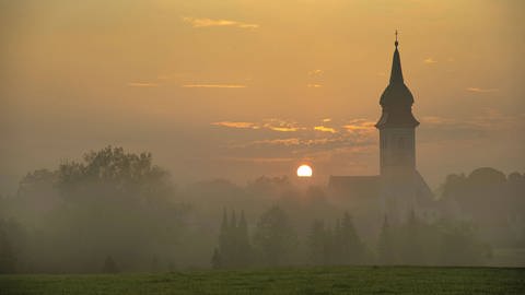 Sonnenaufgang in Rottenbuch hinter der Kirche Mariä Geburt, Kreis Weilheim-Schongau, Bayern (Foto: IMAGO, alimdi)