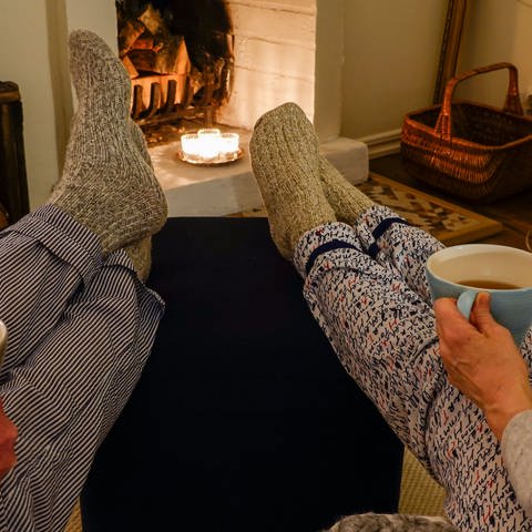 A couple sit together drinking tea with wool socks in front of fireplace Symbolfoto (Foto: picture-alliance / Reportdienste, Picture Alliance)