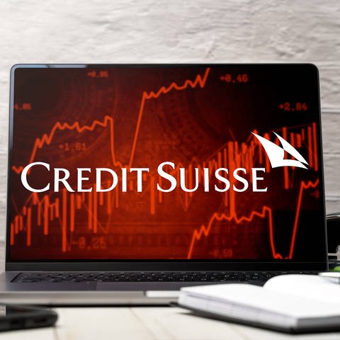 white Credit Suisse bank logo on a laptop computer with red stock chart symbols (Foto: IMAGO, IMAGO / Bihlmayerfotografie)