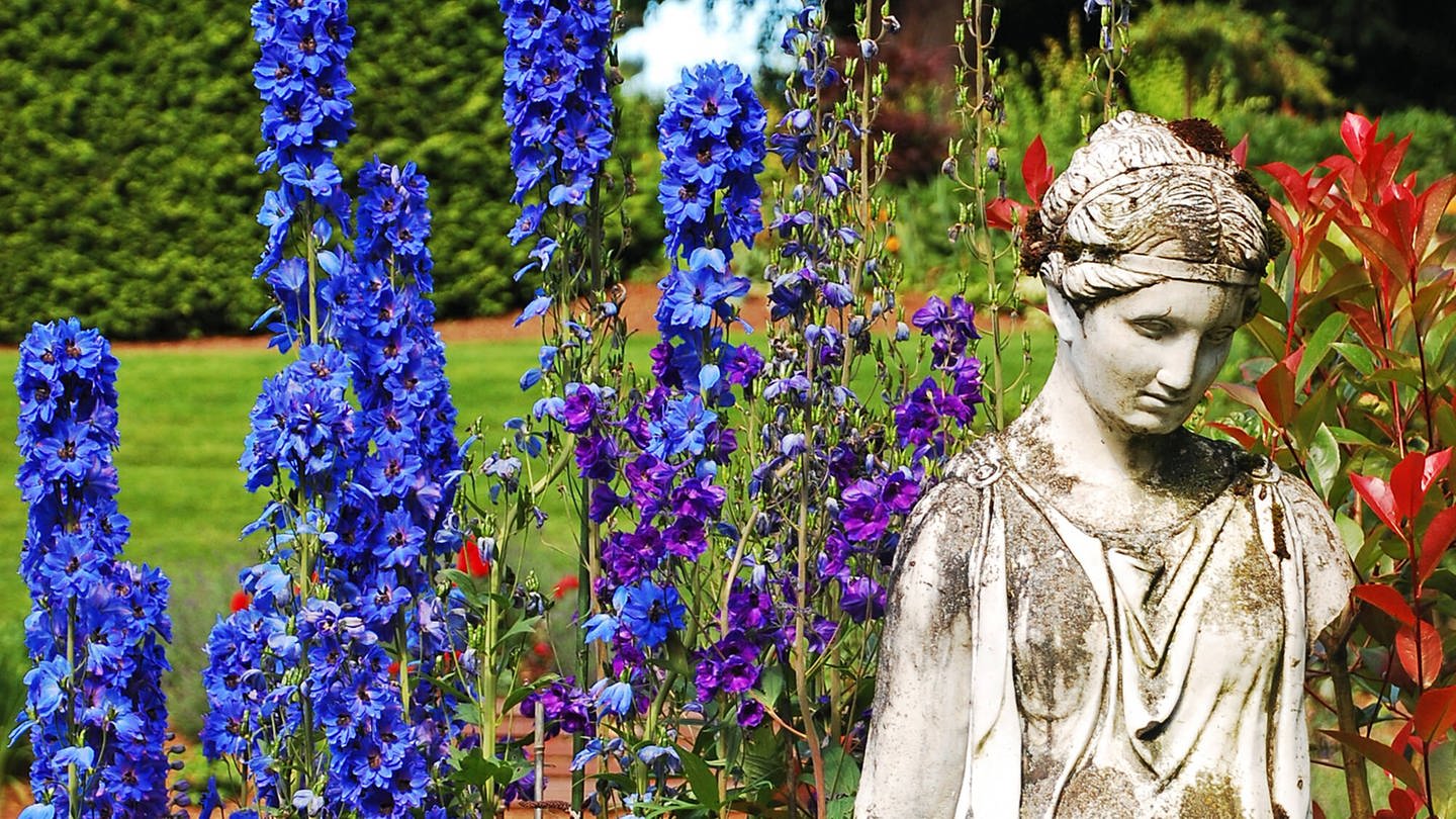Göttinnenstatue in frühlingshaftem Blumenbeet (Foto: IMAGO, YAY Images)