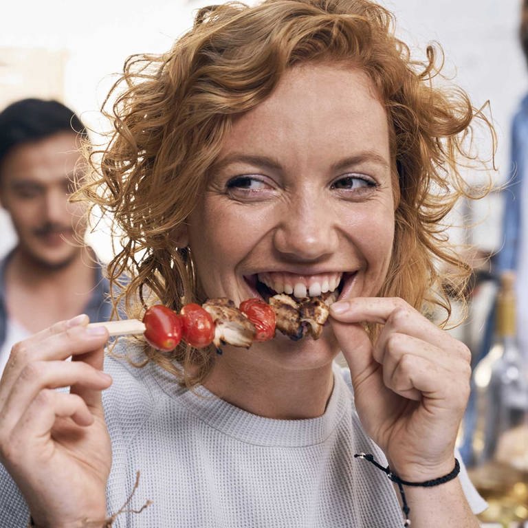 Junge Frau isst einen Grillspieß (Foto: IMAGO, PUBLICATIONxINxGERxSUIxAUTxHUNxONLY PDF01855)