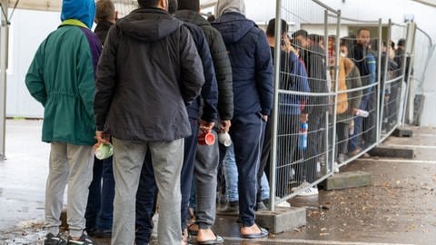 In der Landeserstaufnahmestelle (LEA) warten Flüchtlinge in einer Schlange vor der Essensausgabe.  (Foto: picture-alliance / Reportdienste, picture alliance/dpa | Stefan Puchner)