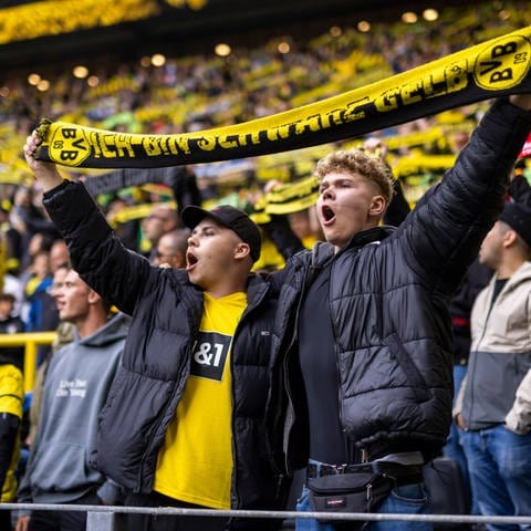Fans von Borussia Dortmund halten die Schals hoch und singen (Foto: IMAGO, IMAGO / Moritz Müller)