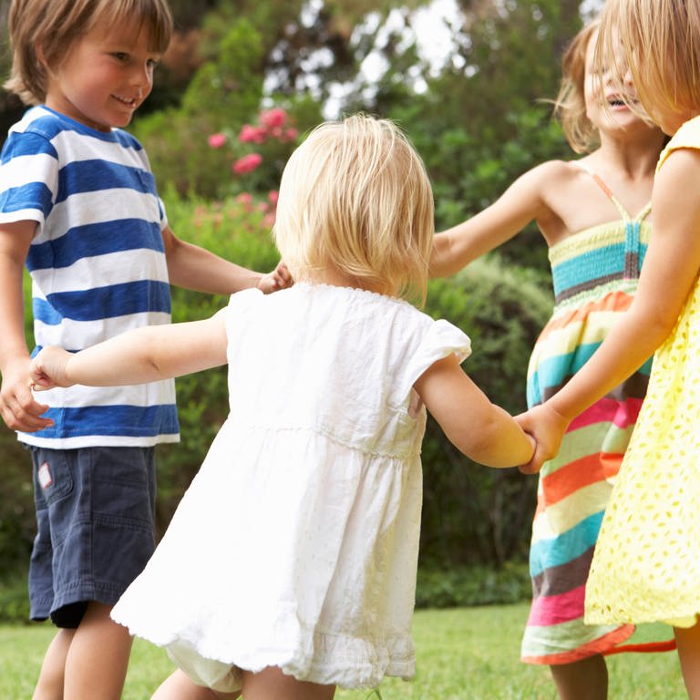 Mehrere Kinder halten sich an den Händen und stehen in einem Kreis zusammen (Foto: IMAGO, IMAGO / Shotshop)