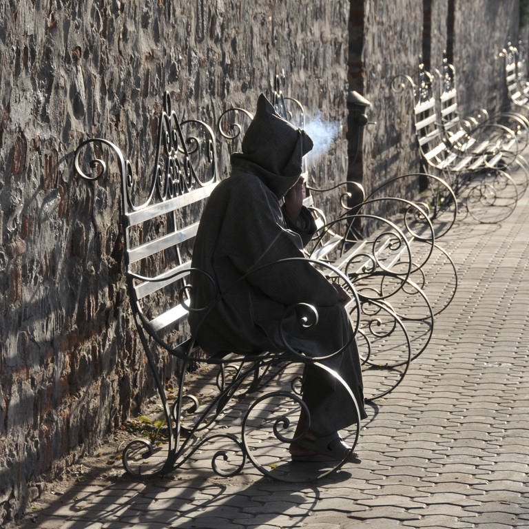 Person sitzt auf einer Bank und raucht (Foto: IMAGO, imagebroker)
