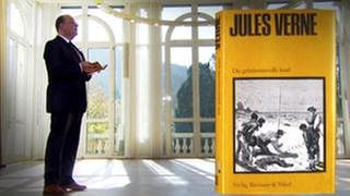 Denis Scheck und daneben das Buch "Die geheimnisvolle Insel" von Jules Verne (Foto: SWR, SWR -)