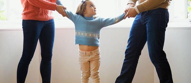 Eine Frau und ein Mann zerren jeweils an dem Arm einen kleinen Mädchens, welches in der Mitte von beiden steht. (Foto: Colourbox, Model Foto: Colourbox.de -)