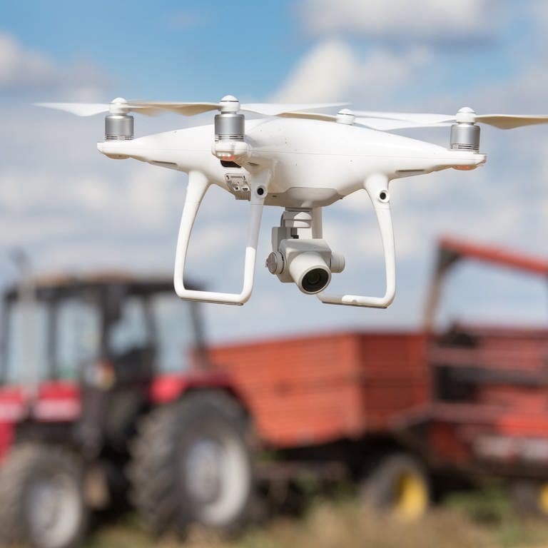 Eine Drone fliegt vor einem Traktor (Foto: IMAGO, agefotostock)
