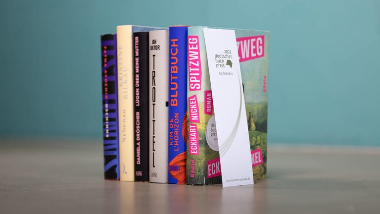 Die Bücher der Shortlist zum Deutschen Buchpreis 2022 stehen nebeneinander (Foto: Pressestelle, vntr.media)