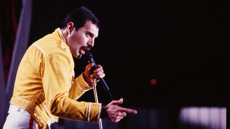 Queen-Frontmann Freddie Mercury beim Live-Aid Konzert von Queen in seiner ikonischen, gelben Jacke (Foto: picture-alliance / Reportdienste, United Archives / ZIK Images)