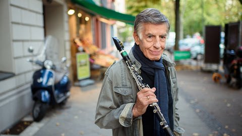 Rolf Kühn, Jazzmusiker und Komponist, steht im Bezirk Charlottenburg auf einem Gehweg und hält seine Klarinette in der Hand.  (Foto: picture-alliance / Reportdienste, picture alliance/dpa | Foto: Gregor Fischer)
