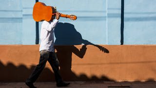 Mann unterwegs mit einer Gitarre auf der Schulter (Foto: imago images, IMAGO / Westend61)