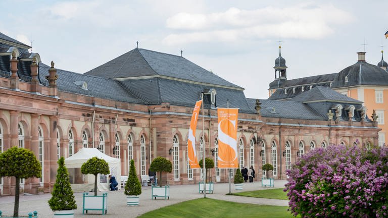 Schwetzinger Schloss mit orangefarbenen Flaggen der Schwetzinger SWR Festspiele davor (Foto: SWR, SWR - Markus Palmer)
