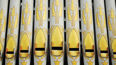 Weiße Orgelpfeifen mit knallig-gelb bemalten Mustern. (Foto: IMAGO, IMAGO / imagebroker)