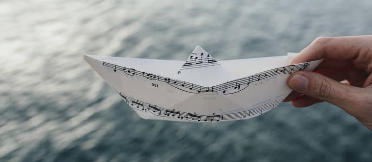 Ein Papierschiff aus Noten (Foto: IMAGO, IMAGO / Westend61)