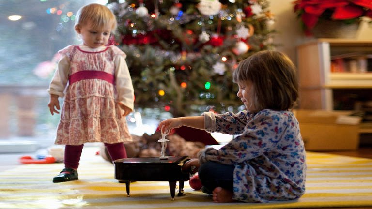 Two young sisters listening to toy piano music box at Xmas, 22.09.2014 (Foto: IMAGO, IMAGO / xKinzieRiehmx)