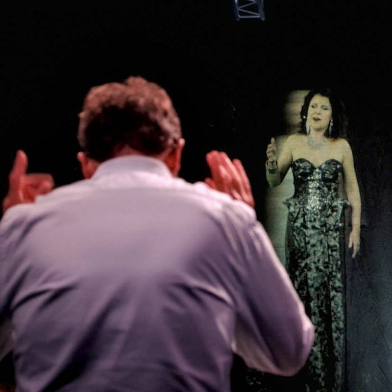 Dirigent, dahinter Hologramm einer Frau (Foto: SWR, nmzMedia)