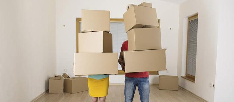Ein Paar steht in einer Wohnung mit Umzugskisten in den Händen (Foto: Getty Images, Thinkstock -)