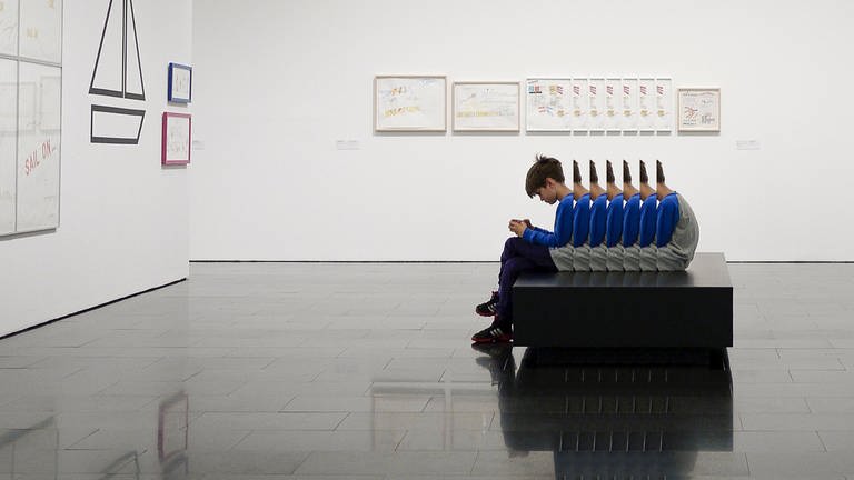 Junge sitzt im Museum (Foto: Unsplash)