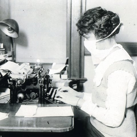 Schreibkraft mit Mund-Nasen-Schutz während der Spanischen Grippe um 1918 (Foto: picture-alliance / Reportdienste, picture-alliance / akg-images)