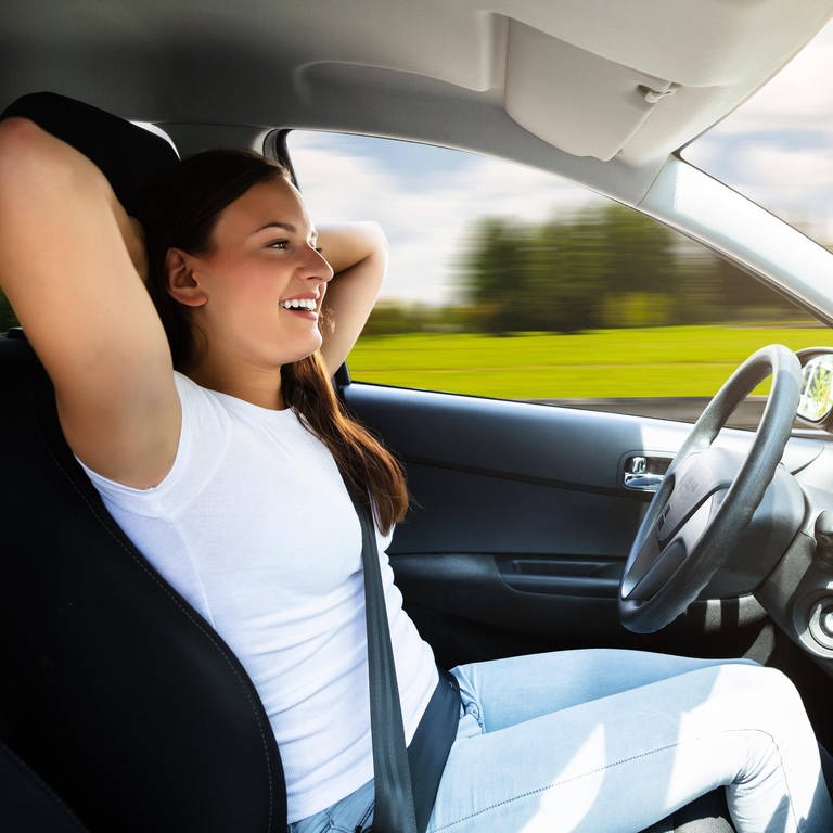 Frau in selbstfahrendem Auto lehnt sich entspannt zurück: Wenn uns in Zukunft ein selbstfahrendes Auto zur Arbeit kutschiert, können wir noch eine Runde ausschlafen.  (Foto: IMAGO, imago images / Panthermedia)