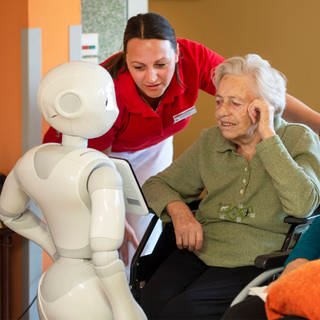 Der humanoide Roboter Pepper kommuniziert in einem Seniorenwohnhaus in Bischofswerda mit Bewohnerinnen und einer Pflegekraft (Foto: imago images, imago images / Norbert Millauer)